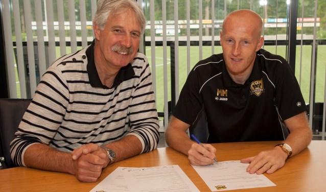 Onder toeziend oog van FC Winterswijk-voorzitter Gerrit te Kolste tekent Martijn Meerdink zijn contract als trainer van het D1-elftal. Foto: Marco ter Haar.