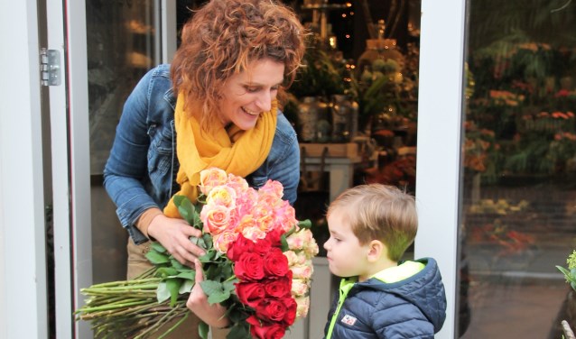Janet Buiting van Altijd Bloemen laat haar jonge klant Ruben ruiken hoe heerlijk de rozen geuren. Foto: Lydia ter Welle