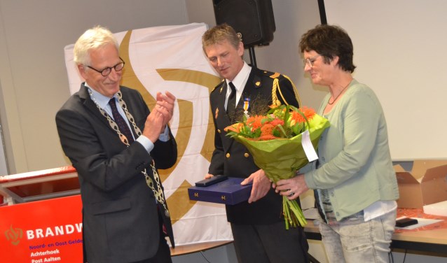 Koninklijke onderscheiding voor Tonny Graven, bloemen voor zijn vrouw Rita. Links burgemeester Arnold Gerritsen. Foto: Karin Stronks