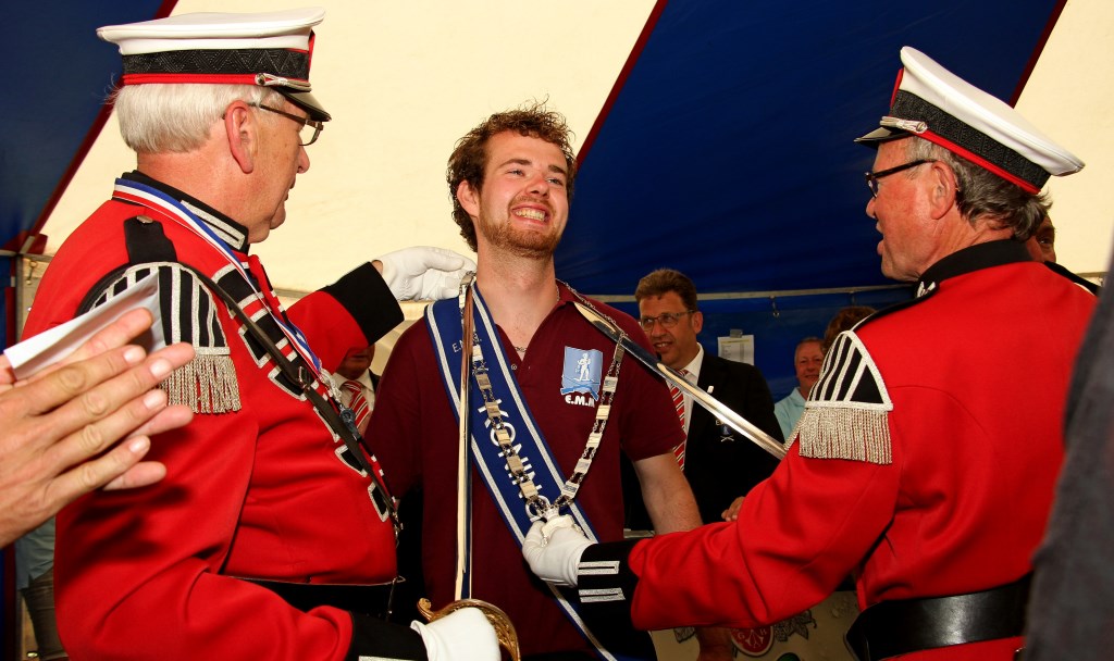 Commandant Jan van der Lende (l.) en adjudant Theo Jaaltink hangen het zilver om bij een trotse schutterskoning Mike Claver. Foto: Achterhoekfoto.nl/Liesbeth Spaansen