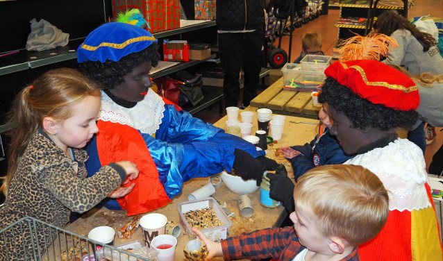 Pieten helpen de kinderen met vogelvoederbakjes knutselen. Foto: Hans Wonink
