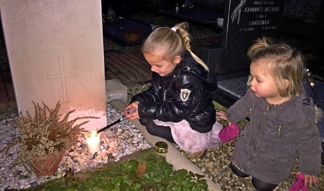 Kinderen steken kaarsjes aan bij een oorlogsgraf in Olburgen. Foto: PR