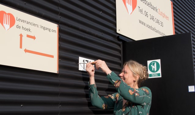 Annelies de Jonge schroeft het nieuwe huisnummer op het pand van de voedselbank. Foto: PR