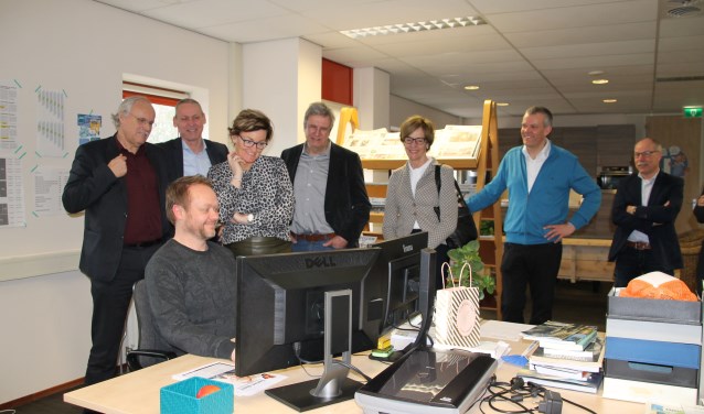 Het college kijkt toe, hoe vormgever Nick Oostendorp bezig is met de gemeentepagina's van Oost Gelre, die wekelijks in de Elna en de Groenlose Gids worden gepubliceerd. Foto: Lydia ter Welle
