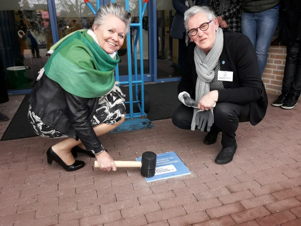 Wethouder Marijke van Haaren en Gerri Bannink leggen de tegel. Foto: Gemeente Berkelland
