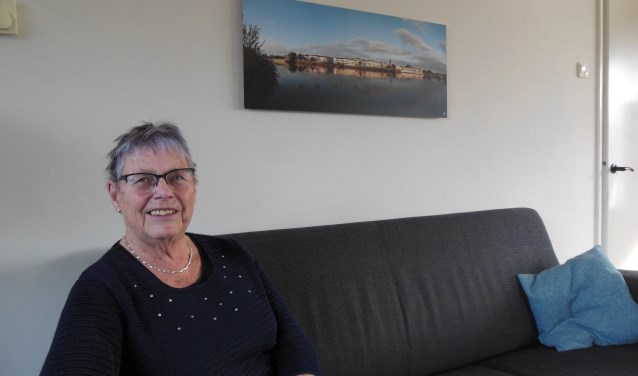 Alie Beker-Beumer onder een ingelijste foto waarop onder meer haar ouderlijk huis prijkt. “Mijn vader en moeder stelden hun leven in de waagschaal.” Foto: Eric Klop