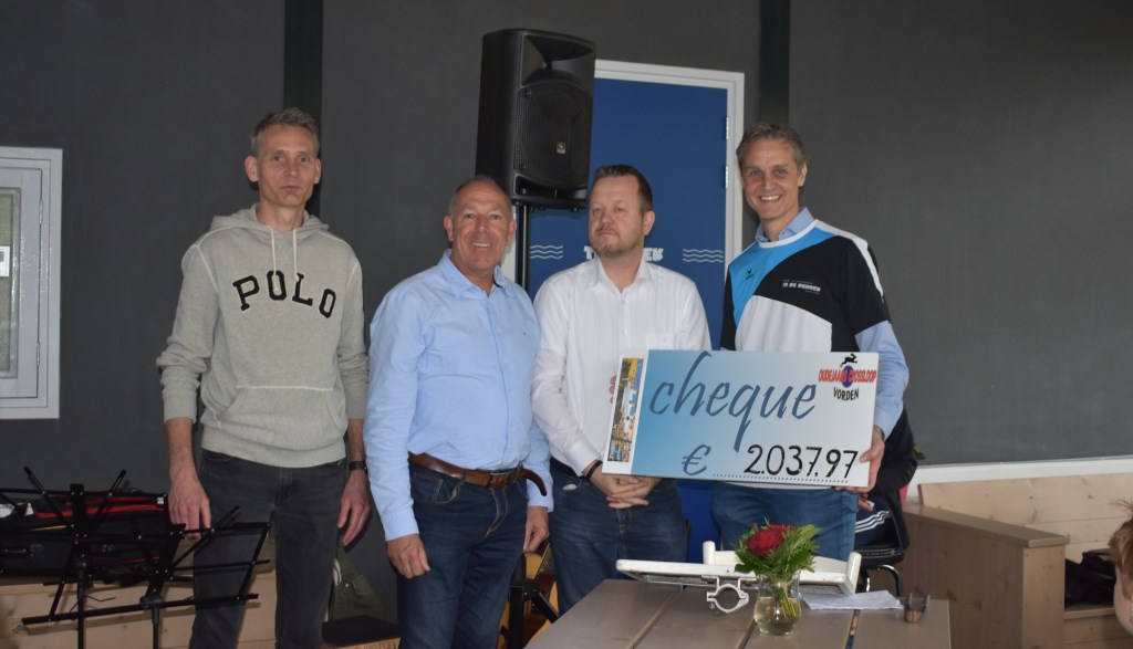 Het bestuur van de Oudejaarscrossloop een cheque uit aan de penningmeester van het zwembad voor de aanleg van een beachvolleybalveld. Foto: PR