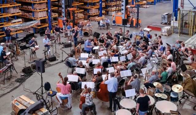 Ruim honderd muzikanten en zangers repeteren in het magazijn van Eurobolt. Foto: Burry van den Brink