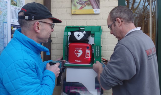 Gerrit Otten (l) en Reinold Haaring bevestigden zaterdag de nieuwe AED aan de muur bij 't Wapen van 't Medler. Foto: Jan Hendriksen