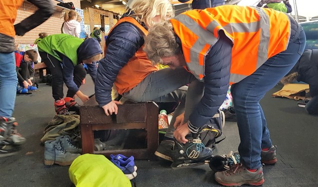 Martje Eggens helpt bij het aantrekken van de schaatsen. Foto: Alice Rouwhorst