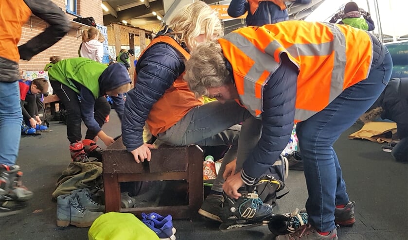 Martje Eggens helpt bij het aantrekken van de schaatsen. Foto: Alice Rouwhorst
