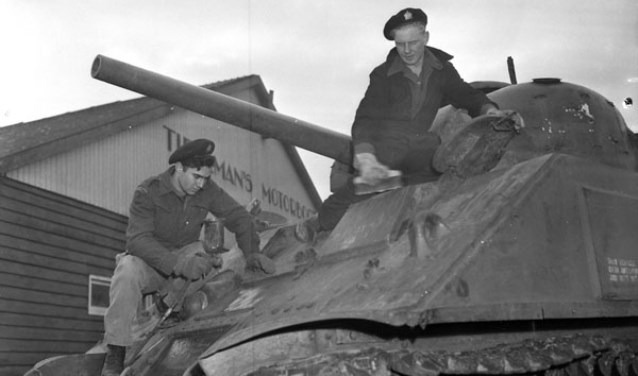 Soldaten poetsen de Sherman M4A4 tank, voor de werkplaats van Tieleman op 22 november 1945. Deze tank staat nu aan de Torontostraat in Doetinchem (Foto: Collectionscanada)