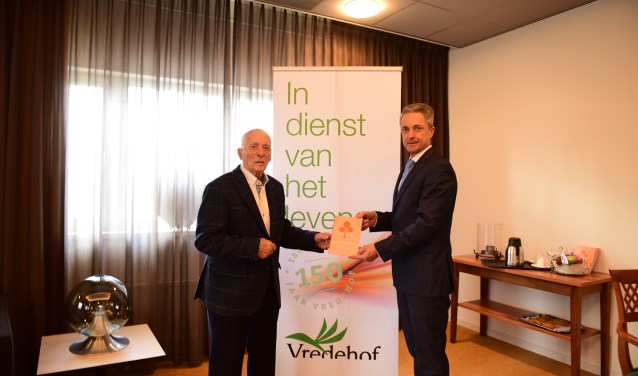 Dhr. Kok (links) krijgt het herinneringsboekje van Pedro Swier (rechts). Foto: PR