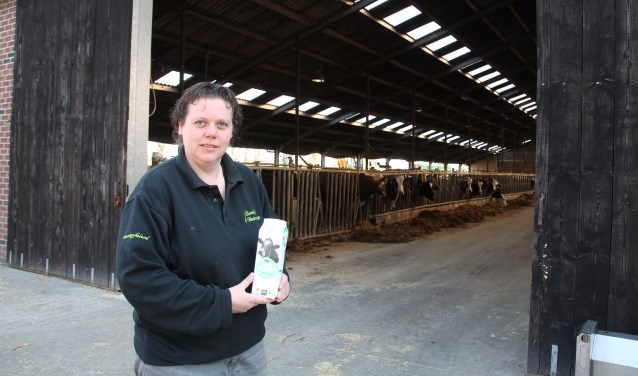 Suzanne Ruesink met een pak Beter Leven-zuivel, voor de stal met de 'leveranciers' van de melk. Foto: Lydia ter Welle