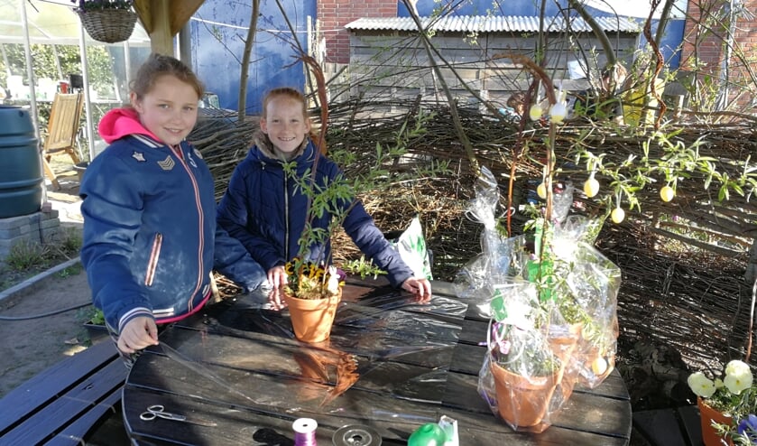 De leerlingen Zuzanna (l) en Britt maken de bloemstukjes voor de wijk klaar. Foto: Rob Weeber