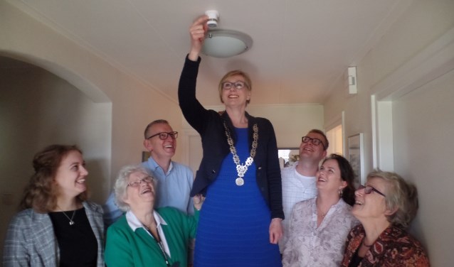 Bewoonster Anneke van Diest (tweede links) kijkt goedkeurend toe hoe burgemeester Marianne Besselink een bewegingssensor in haar woning installeert. Foto: Jan Hendriksen