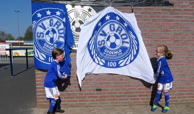 Tristan Wissink (links) en Dieke Gebbink (rechts) onthullen de gedenksteen ‘100 jaar S.V. Grol’. Foto: Theo Huijskes