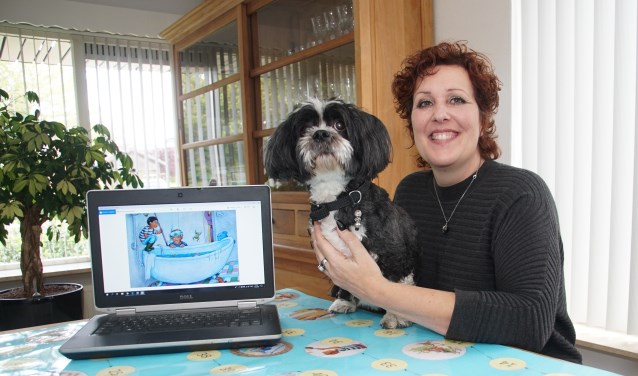 Bettina IJzendoorn, met een afbeelding van het boek op de pc, en met haar hond, die in een verhaal Guusje heet. Foto: Frank Vinkenvleugel