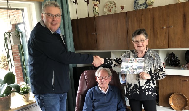 Medewerker Franko reikt het boekje uit aan de heer en mevrouw Ruesink. Foto: PR