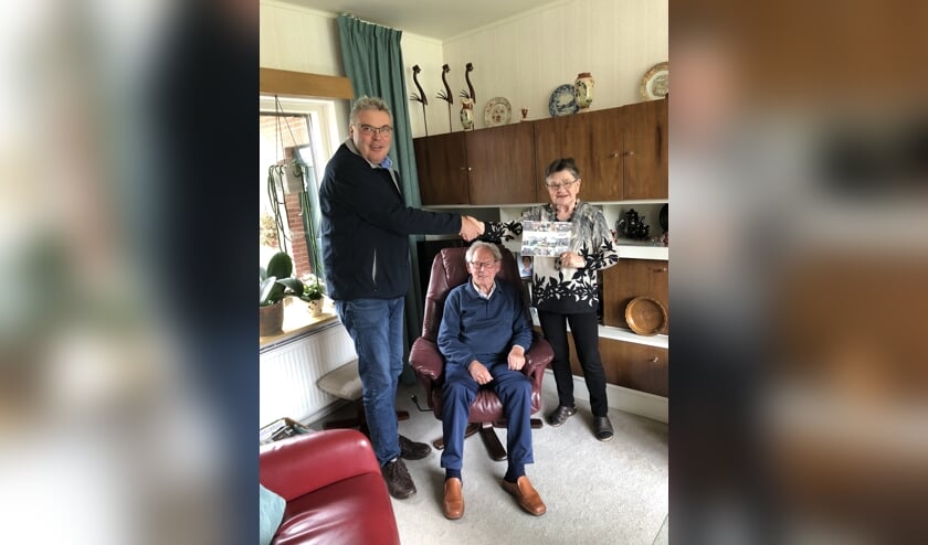 Medewerker Franko reikt het boekje uit aan de heer en mevrouw Ruesink. Foto: PR