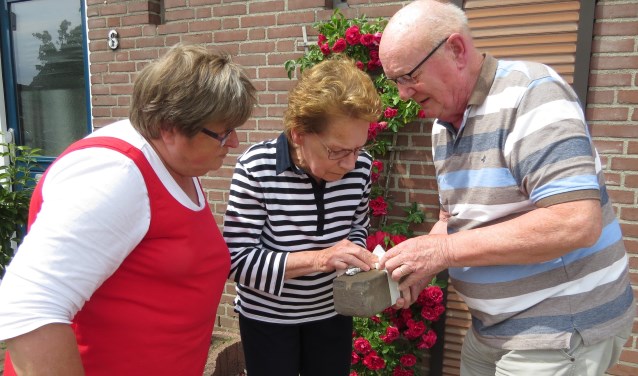 Wil Hondorp (rechts) geeft aan Toos Groenen (midden) en Annie Groenen uitleg over de unieke straatsteen. Foto: Josée Gruwel