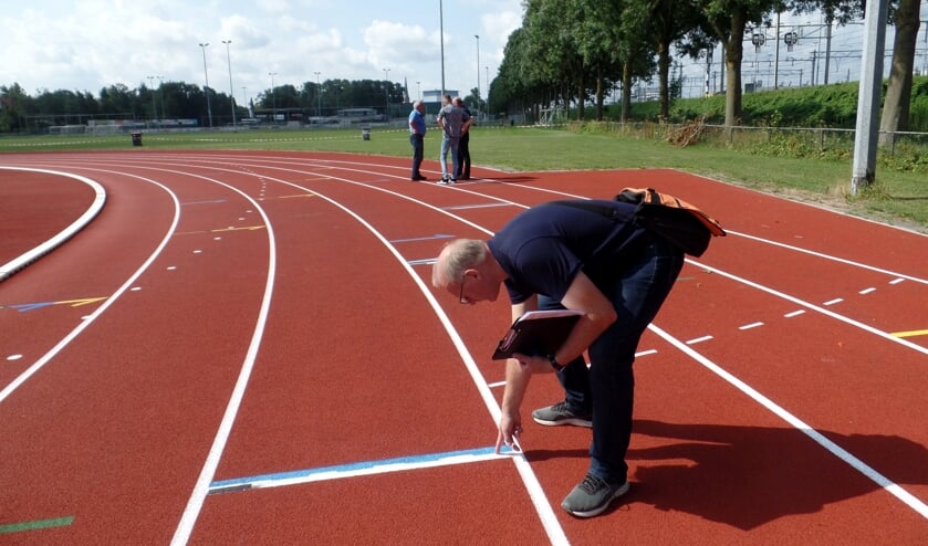 Rik Hoevers van de Atlekiekunie bekijkt de lijnen op de baan. Op de achtergrond voorzitter Anton Kruiderink (l), wethouder Matthijs ten Broeke (m) en Jaap Verhagen van de gemeente. Foto: Meike Wesselink