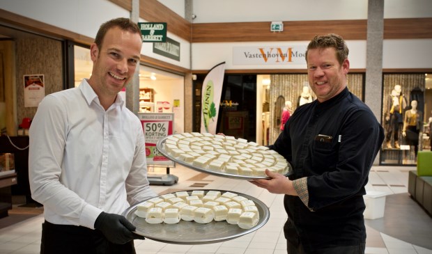 Dennis van Line-Up Events en John Hoetjes van Bakkerij Kees Zoon delen gebakjes uit aan het winkelend publiek.
