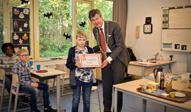 Burgemeester Mans reikt de cheque uit aan Danny van groep 8 van de Antoniusschool
