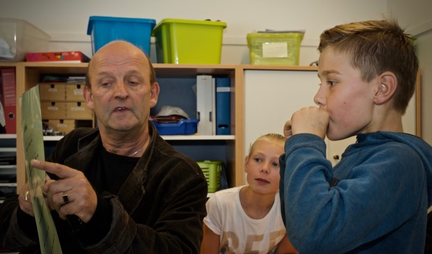 Eugène Vriend leert de leerlingen van de Paulusschool hoe je Kortjakje speelt op de mondharmonica.