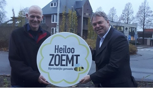 Wethouder Rob Opdam en wijkbeheerder Gerard Bak ontvangen het officiële bord ‘Heiloo zoemt’. Deze krijgt een mooi plekje op de ‘nieuwe’ rotonde met plantvakken voor het gemeentehuis.