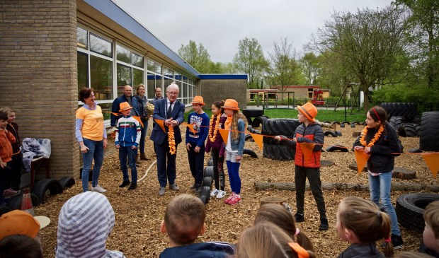 Burgemeester Hans Romeyn knipt de vlaggetjeslijn door en daarmee is het speelveld geopend.
Directeur Annemiek van de Vliet, leerlingen van de leerlingenraad en de ouders van de werkgroep, Erwin Luten, Kirsten Staffhorst en Harrold Deelen kijken toe.
