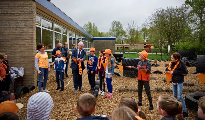 Burgemeester Hans Romeyn knipt de vlaggetjeslijn door en daarmee is het speelveld geopend.
Directeur Annemiek van de Vliet, leerlingen van de leerlingenraad en de ouders van de werkgroep, Erwin Luten, Kirsten Staffhorst en Harrold Deelen kijken toe.