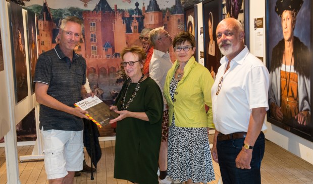 Links Martijn Mulder die een prachtig boek overhandigt aan de gelukkige 2000e bezoeker. Verder vrijwilliger Carla Kager en Jos Hof op de foto.