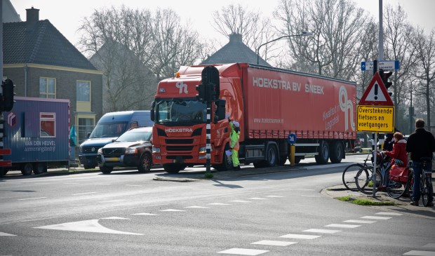 Een vrachtwagen mag de Stationsweg niet in. Een verkeersregelaar wijst hem de juiste weg.