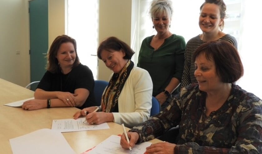 Directeuren Annemiek van de Vliet (de Duif) en Jeanette Braam (Bibliotheek Heiloo) ondertekenen het contract. Natasja Hoebe en Joke van Overbeeke (leescoördinatoren de Duif) en Marieke Ooijevaar (leesconsulent Bibliotheek) kijken toe. 