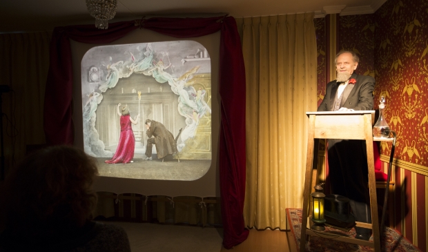 Charles Dickens-acteur Aad Kok met toverlantaarnplaat Krekel bij het Haardvuur