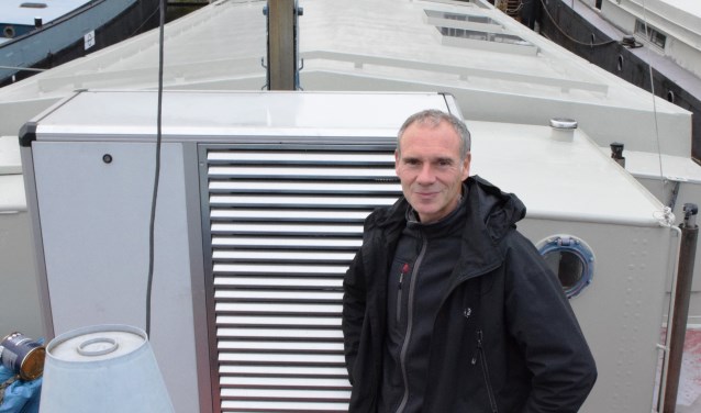 Evert Jan de Vries op de plecht van zijn woonschip, naast de warmtepomp.