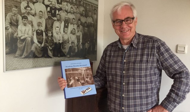 Hans Jonker met het boek bij een foto van werknemers van Bensdorp in vroegere tijden.