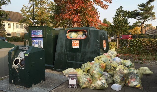 De zakken liggen naast de container.