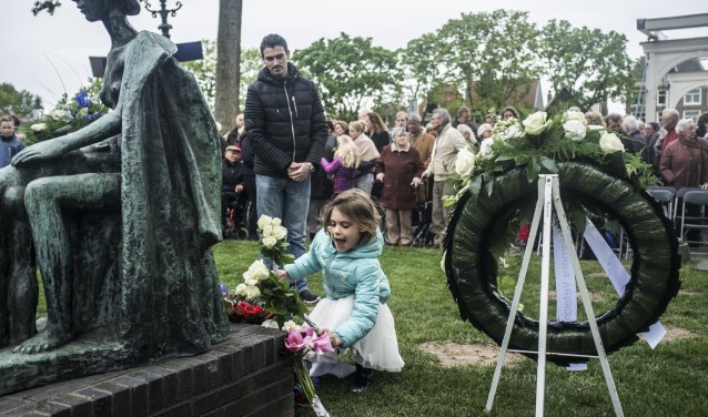Kinderen leggen bloemen bij het monument.