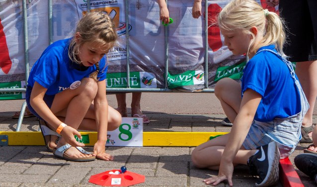 Twee jongedames in de strijd voor het knikkerkampioenschap van Huizen.