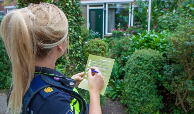 De wijkagent vult een waarschuwingsfolder in, waar ze aankruist waar bewoners op moeten letten.