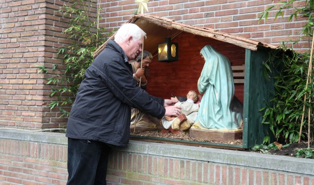 Kees Kuijpers rangschikt de buitenkerststal van de Weesper parochie.