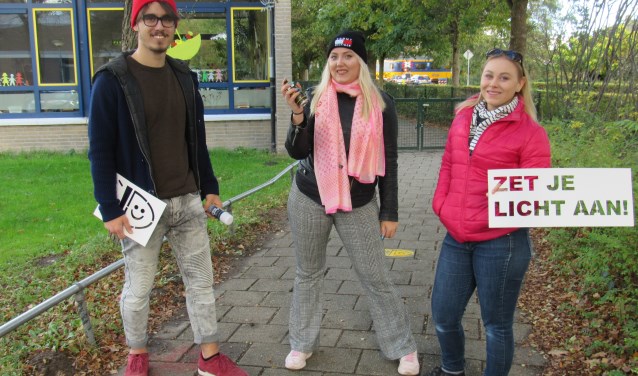 Mees, Else-Meike en Willemijn spoten met spuitkrijt de tekst 'Zet je licht aan' op fietspaden rond scholen.