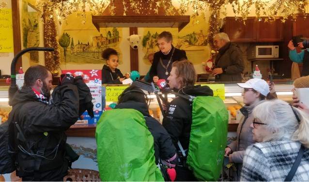 Burgemeester en kinderburgemeester verkopen oliebollen.