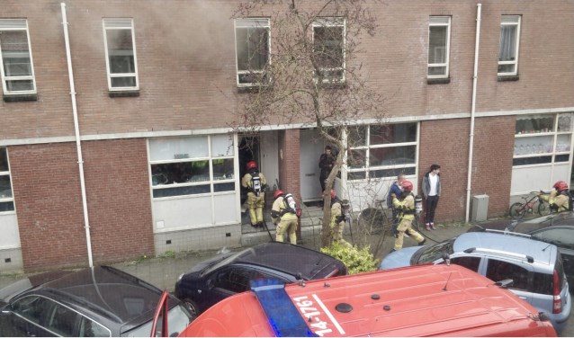 De brandweer breekt de deur open en betreedt de woning.