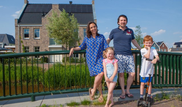 Saskia en Justin en hun kinderen in de Zuidpolder. Op de achtergrond hun nieuwe woning.
