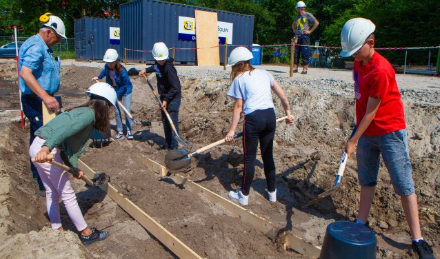 Leerlingen helpen bij het leggen van het fundament van de school.