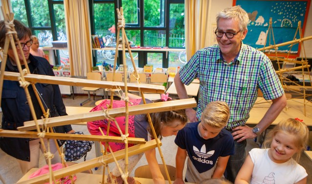 Meester Jaap kijkt naar de bamboe bouwsels.