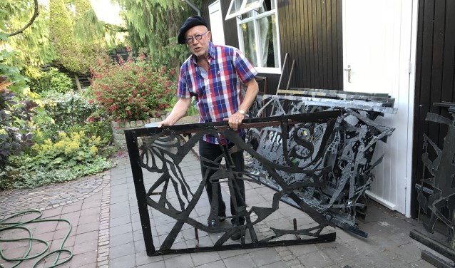 Tekenleraar Hans van Deuren met een deel van het kunstwerk dat hij redde van de sloop. De molen en het wapen van Laren zijn duidelijk herkenbaar.